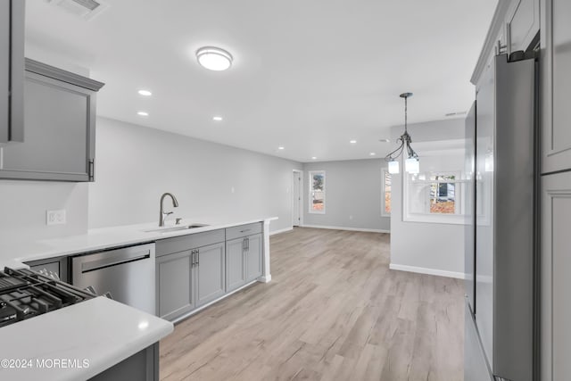 kitchen featuring appliances with stainless steel finishes, light wood-type flooring, gray cabinets, and sink