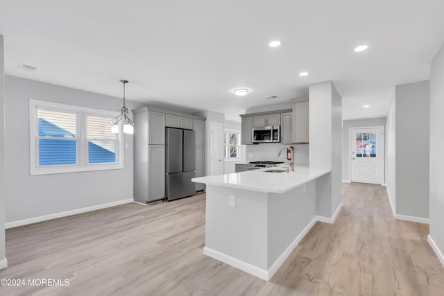 kitchen featuring kitchen peninsula, stainless steel appliances, gray cabinets, and light hardwood / wood-style floors