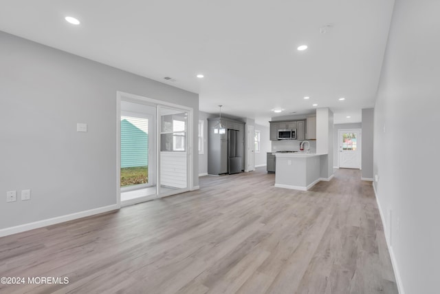 unfurnished living room featuring sink and light hardwood / wood-style flooring