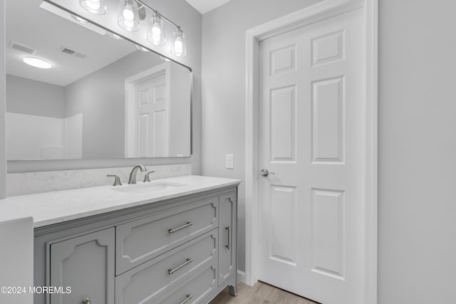 bathroom featuring hardwood / wood-style floors, vanity, and a shower