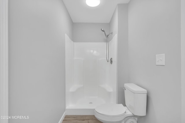 bathroom featuring toilet, wood-type flooring, and walk in shower