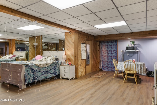 bedroom with hardwood / wood-style floors, a paneled ceiling, and wooden walls