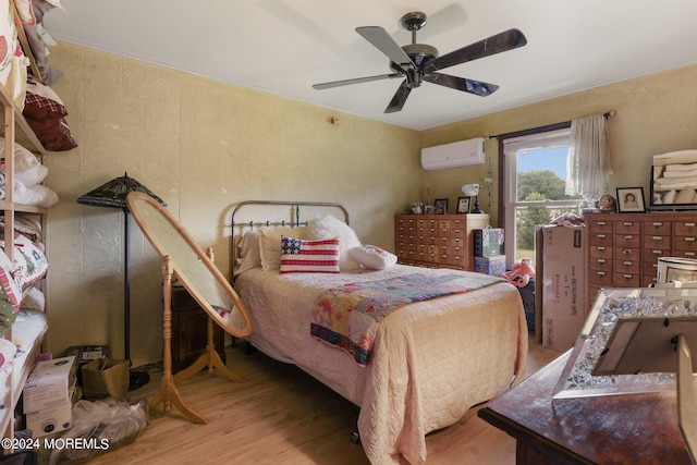 bedroom featuring a wall mounted air conditioner, hardwood / wood-style floors, and ceiling fan