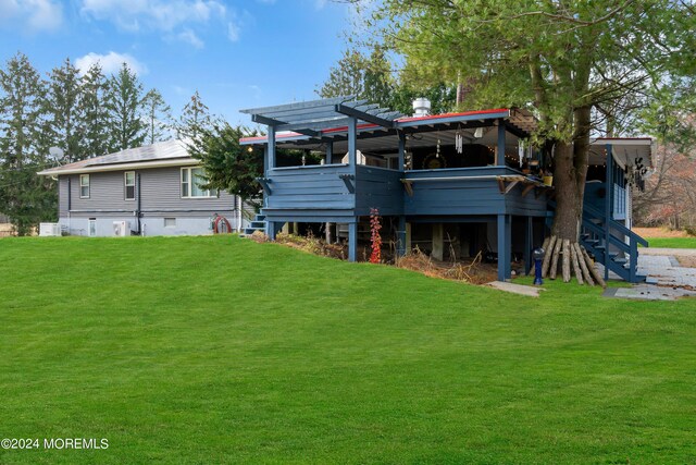 rear view of house featuring a pergola, a deck, and a yard