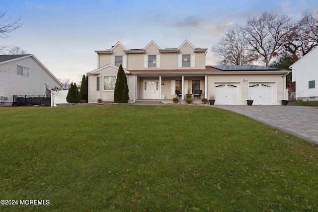 view of front of home with a front yard, solar panels, a porch, and a garage