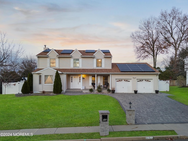 view of front facade featuring solar panels, a yard, a porch, and a garage