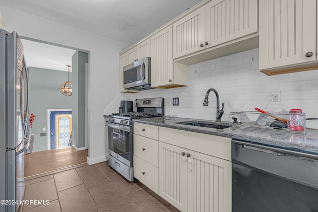 kitchen featuring an inviting chandelier, sink, dark stone countertops, appliances with stainless steel finishes, and tasteful backsplash