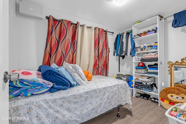 bedroom featuring an AC wall unit and light hardwood / wood-style floors