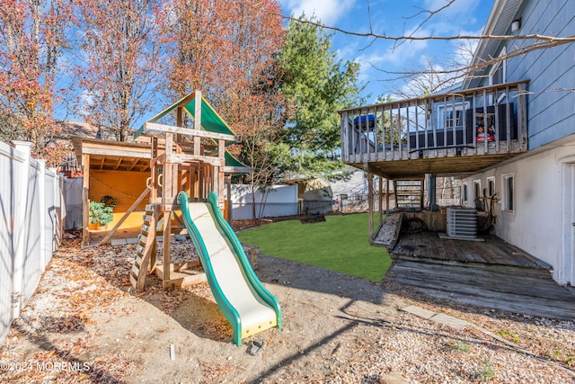 view of playground with a lawn, a deck, and central air condition unit