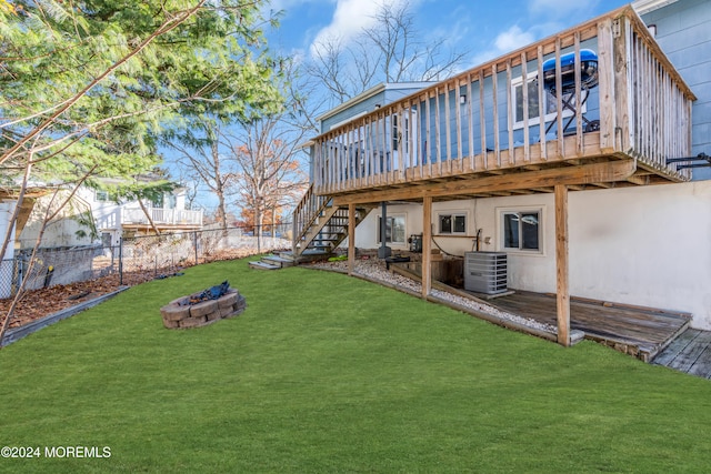 rear view of house featuring central air condition unit, a wooden deck, a yard, and an outdoor fire pit