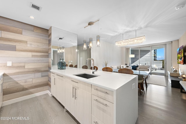 kitchen featuring light hardwood / wood-style flooring, hanging light fixtures, wooden walls, and sink