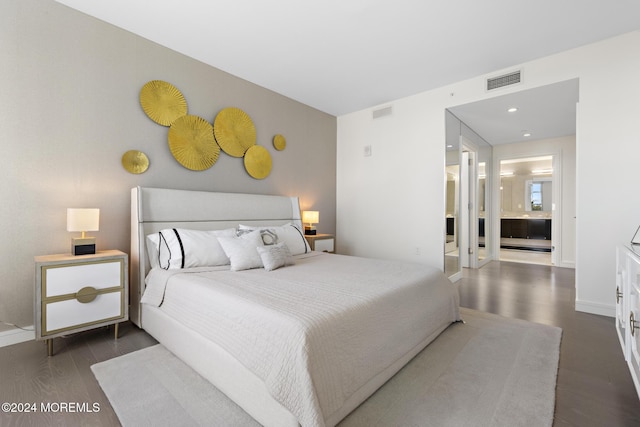 bedroom featuring ensuite bathroom and dark wood-type flooring