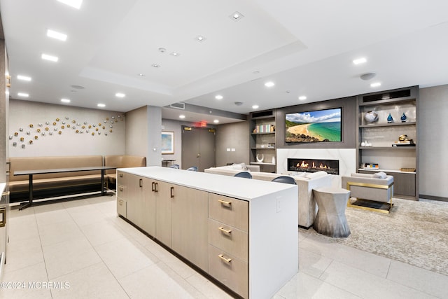 kitchen with a tray ceiling, a high end fireplace, and a kitchen island