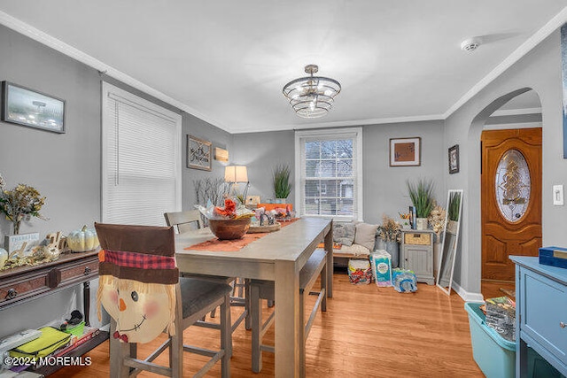 dining room featuring crown molding, light hardwood / wood-style flooring, and a notable chandelier