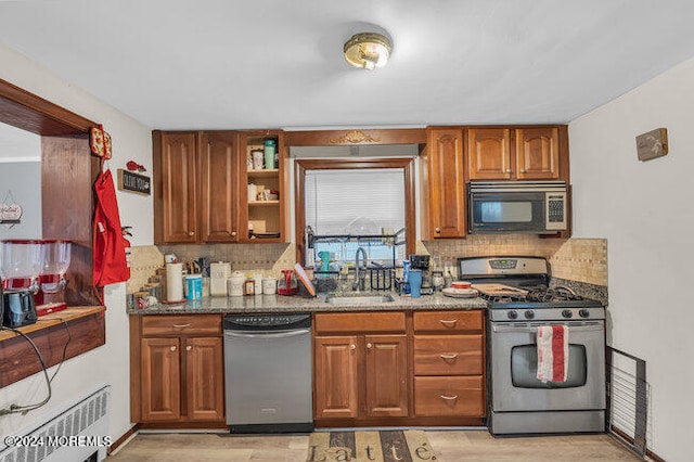 kitchen with backsplash, stainless steel appliances, dark stone counters, and sink