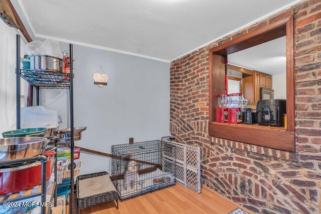 interior space featuring crown molding, wood-type flooring, and brick wall