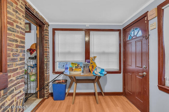 foyer with breakfast area, light hardwood / wood-style floors, crown molding, and brick wall