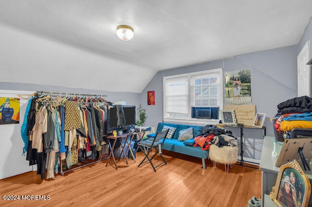 bedroom with light hardwood / wood-style floors, vaulted ceiling, and cooling unit