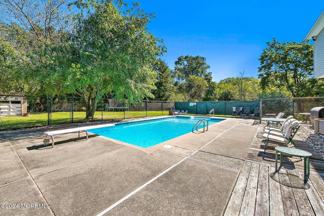 view of pool featuring a patio area, a diving board, and a trampoline