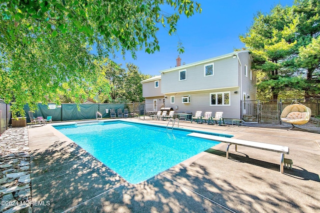 view of swimming pool with a diving board and a patio area