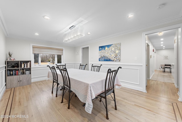 dining area with light wood-type flooring and ornamental molding