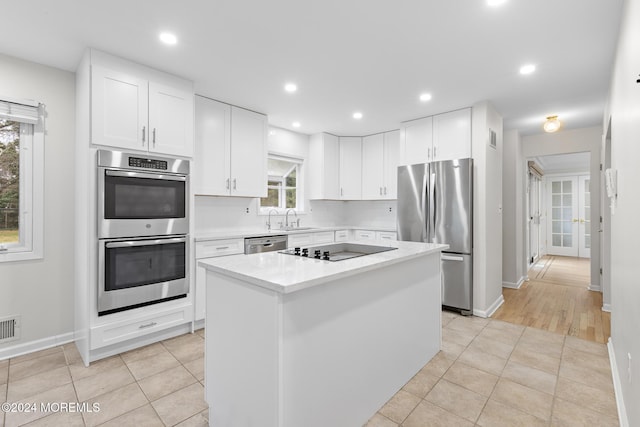 kitchen with white cabinetry, sink, a kitchen island, and stainless steel appliances