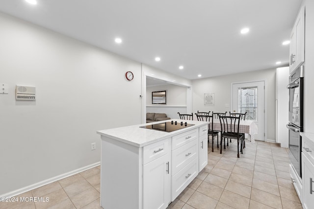 kitchen with light tile patterned floors, black electric cooktop, white cabinetry, and a kitchen island