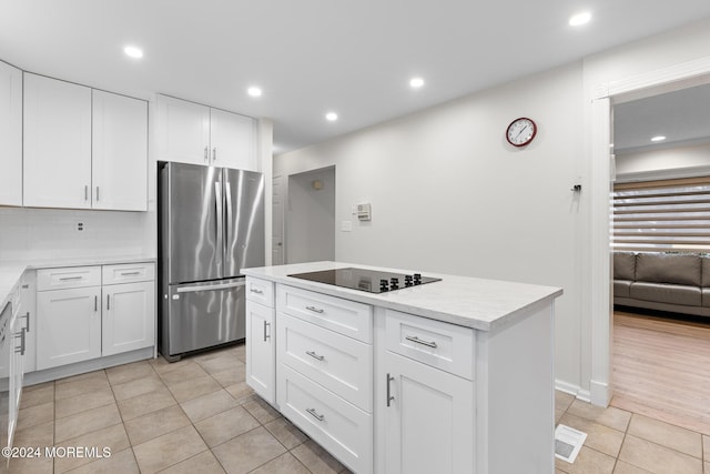 kitchen with stainless steel refrigerator, black electric stovetop, white cabinets, and a kitchen island