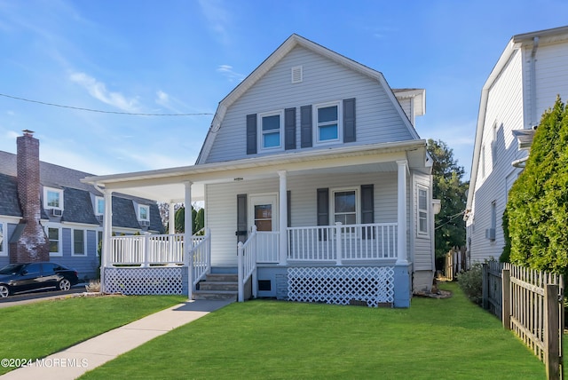 colonial inspired home with covered porch, a gambrel roof, and a front lawn