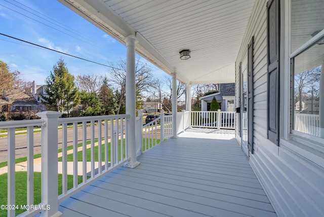 wooden deck featuring a porch and a lawn