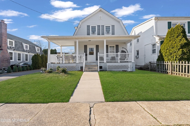 colonial inspired home featuring a gambrel roof, a porch, a front lawn, and fence