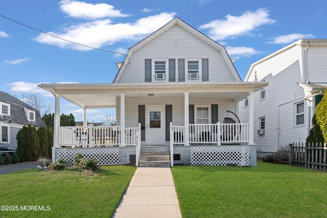 colonial inspired home featuring covered porch, a gambrel roof, a front lawn, and fence