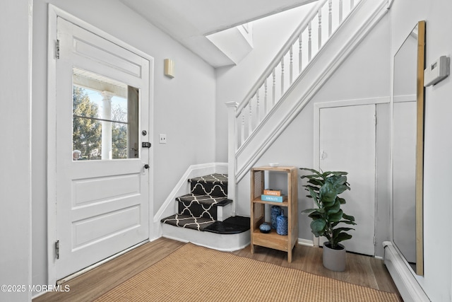 interior space with a baseboard heating unit, wood finished floors, stairway, a skylight, and baseboards