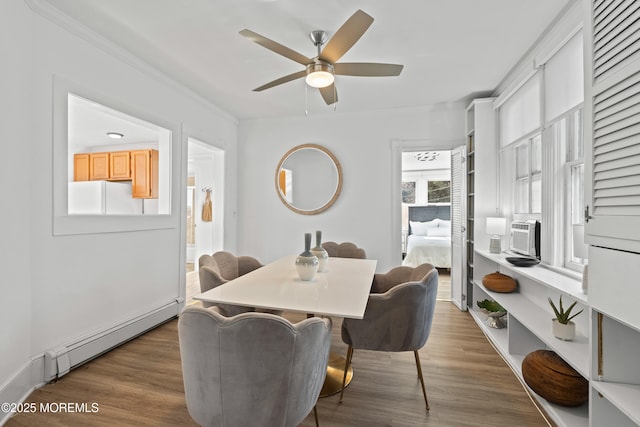 dining area with wood finished floors, crown molding, ceiling fan, and a baseboard radiator