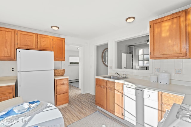 kitchen with white appliances, a sink, light countertops, a baseboard heating unit, and tasteful backsplash