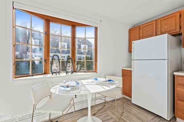 kitchen featuring brown cabinetry, plenty of natural light, light countertops, and freestanding refrigerator