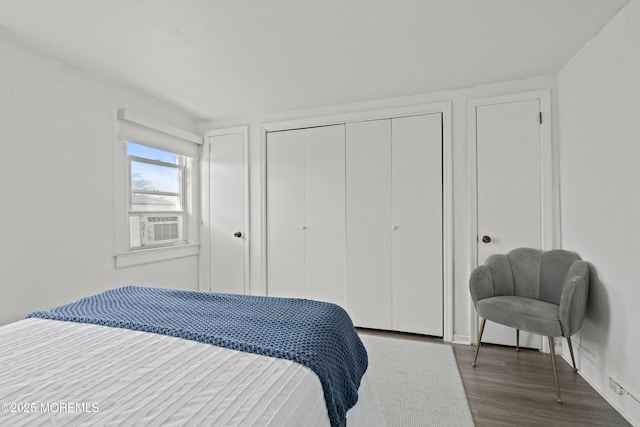 bedroom with a closet, cooling unit, baseboards, and wood finished floors