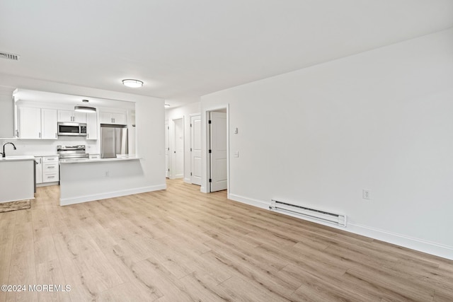 unfurnished living room featuring light hardwood / wood-style flooring, baseboard heating, and sink