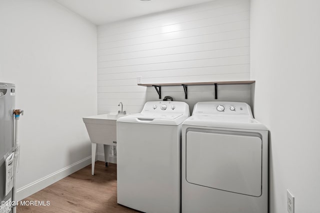 laundry area featuring hardwood / wood-style flooring, washing machine and dryer, sink, and gas water heater