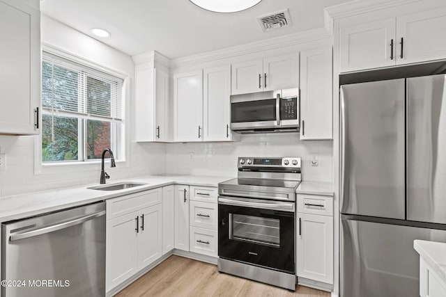 kitchen with white cabinets, appliances with stainless steel finishes, tasteful backsplash, and sink