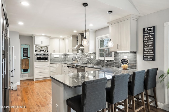 kitchen featuring decorative light fixtures, kitchen peninsula, a breakfast bar area, and stainless steel appliances