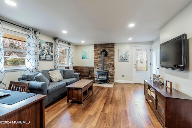 living room with a wood stove, a wealth of natural light, and hardwood / wood-style flooring