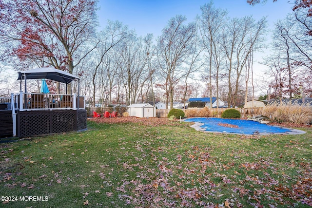 view of yard with a gazebo, a swimming pool side deck, and a storage shed