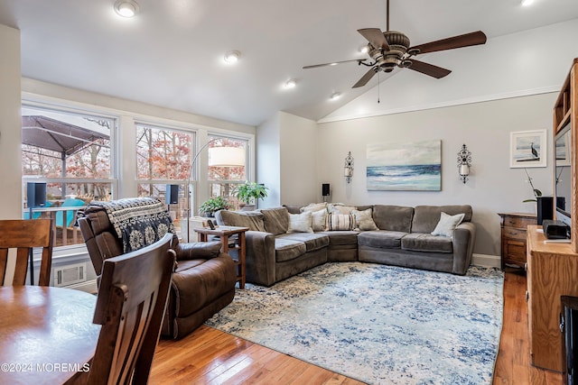 living room with ceiling fan, light hardwood / wood-style floors, and vaulted ceiling