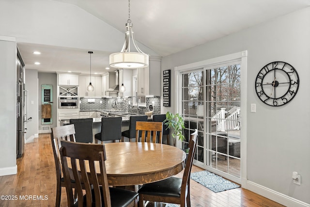 dining space with light hardwood / wood-style flooring and lofted ceiling