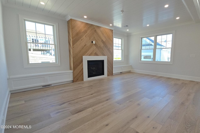 unfurnished living room with a large fireplace, light wood-type flooring, and a wealth of natural light