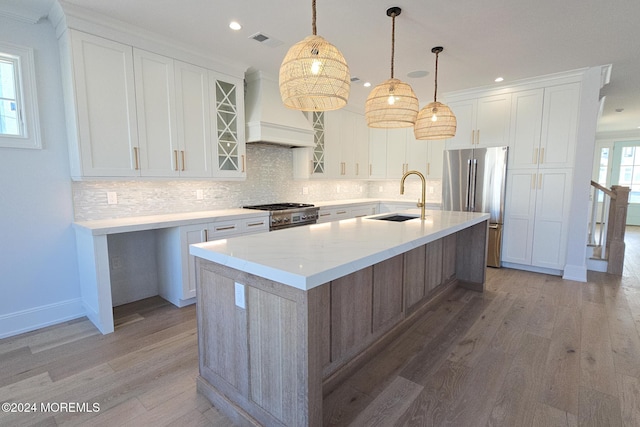 kitchen featuring appliances with stainless steel finishes, white cabinetry, a kitchen island with sink, and sink