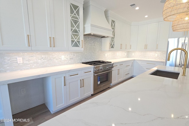 kitchen with custom exhaust hood, light stone counters, stainless steel appliances, and decorative light fixtures