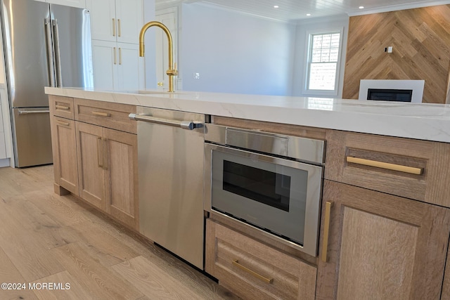 kitchen with light brown cabinets, sink, crown molding, light hardwood / wood-style flooring, and appliances with stainless steel finishes