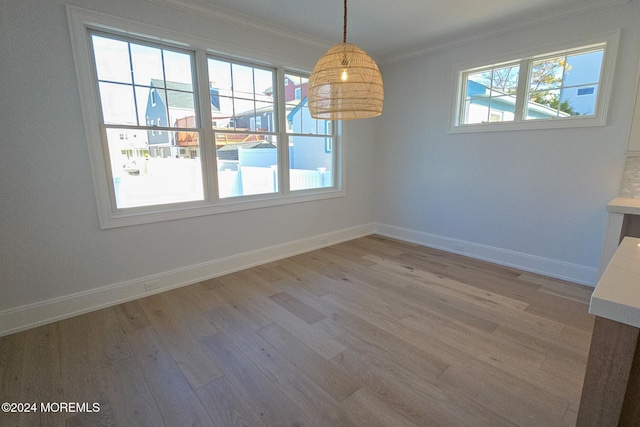 unfurnished dining area with plenty of natural light, light wood-type flooring, and ornamental molding